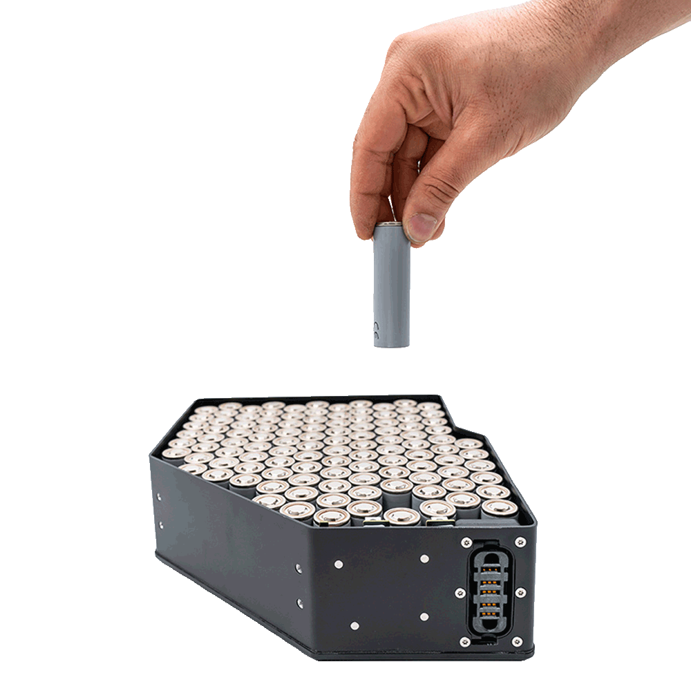 A hand lifting a single cylindrical cell out of an open MAKI battery pack, showing the weld-free repairable cell contacting